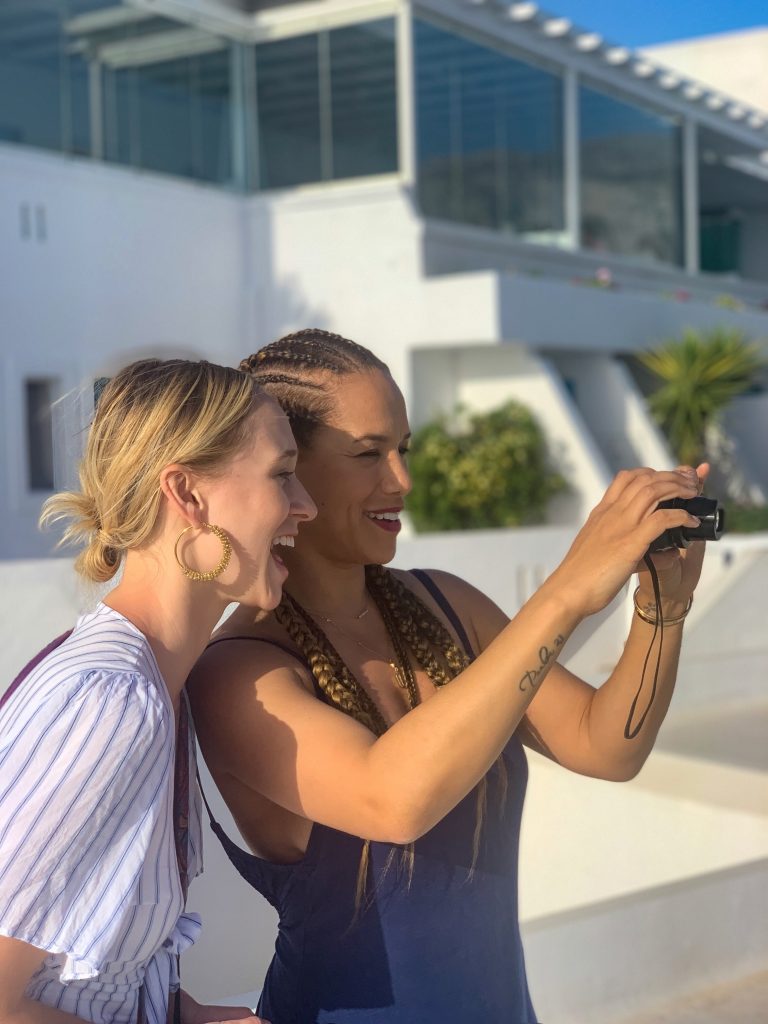 Two women laughing looking into viewer of a Canon camera in Amorgos, Greece.