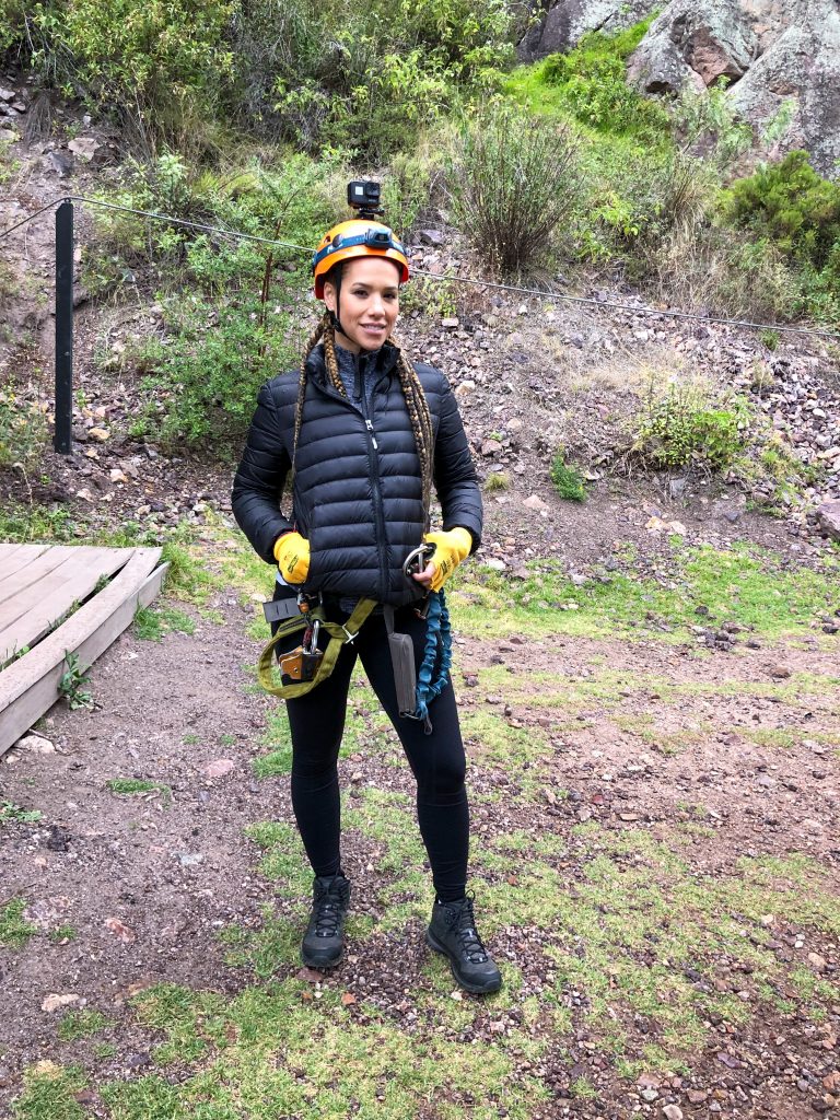 Woman in black wearing climbing gear and a GoPro camera attached to her helmet.