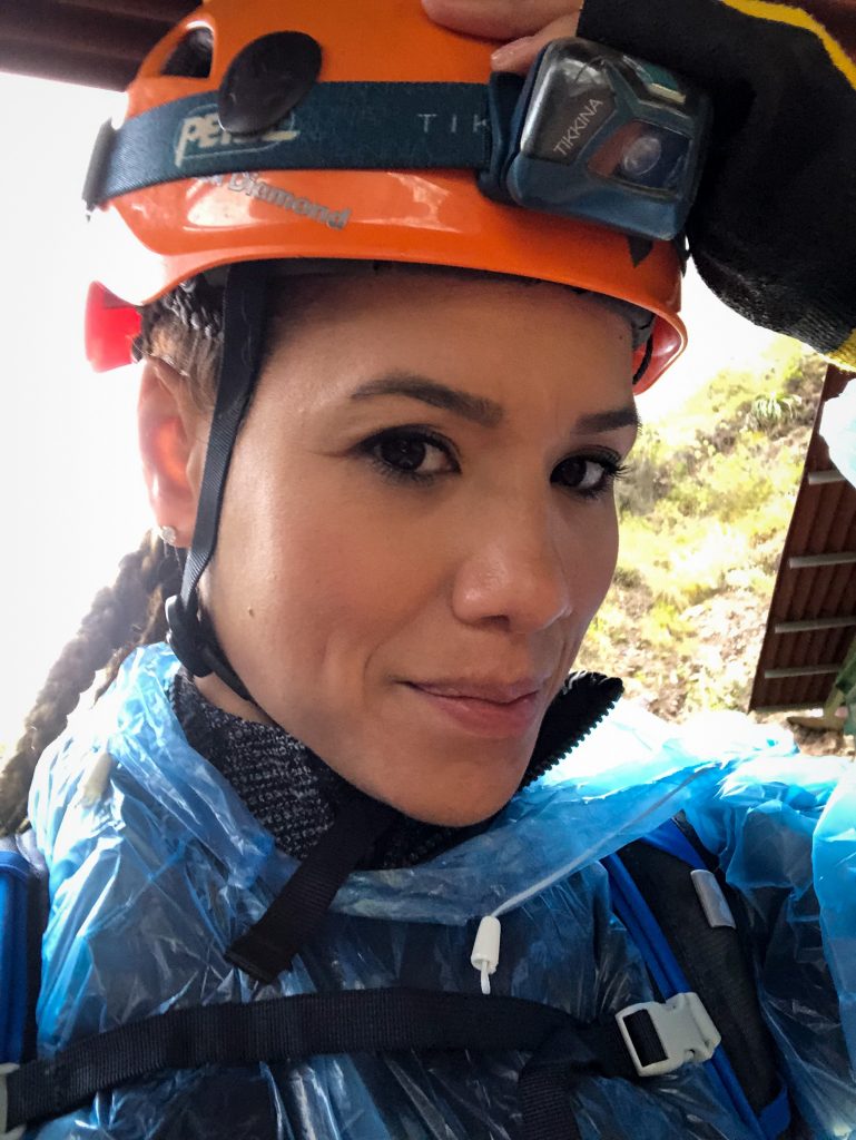 Woman wearing orange helmet and climbing gear.